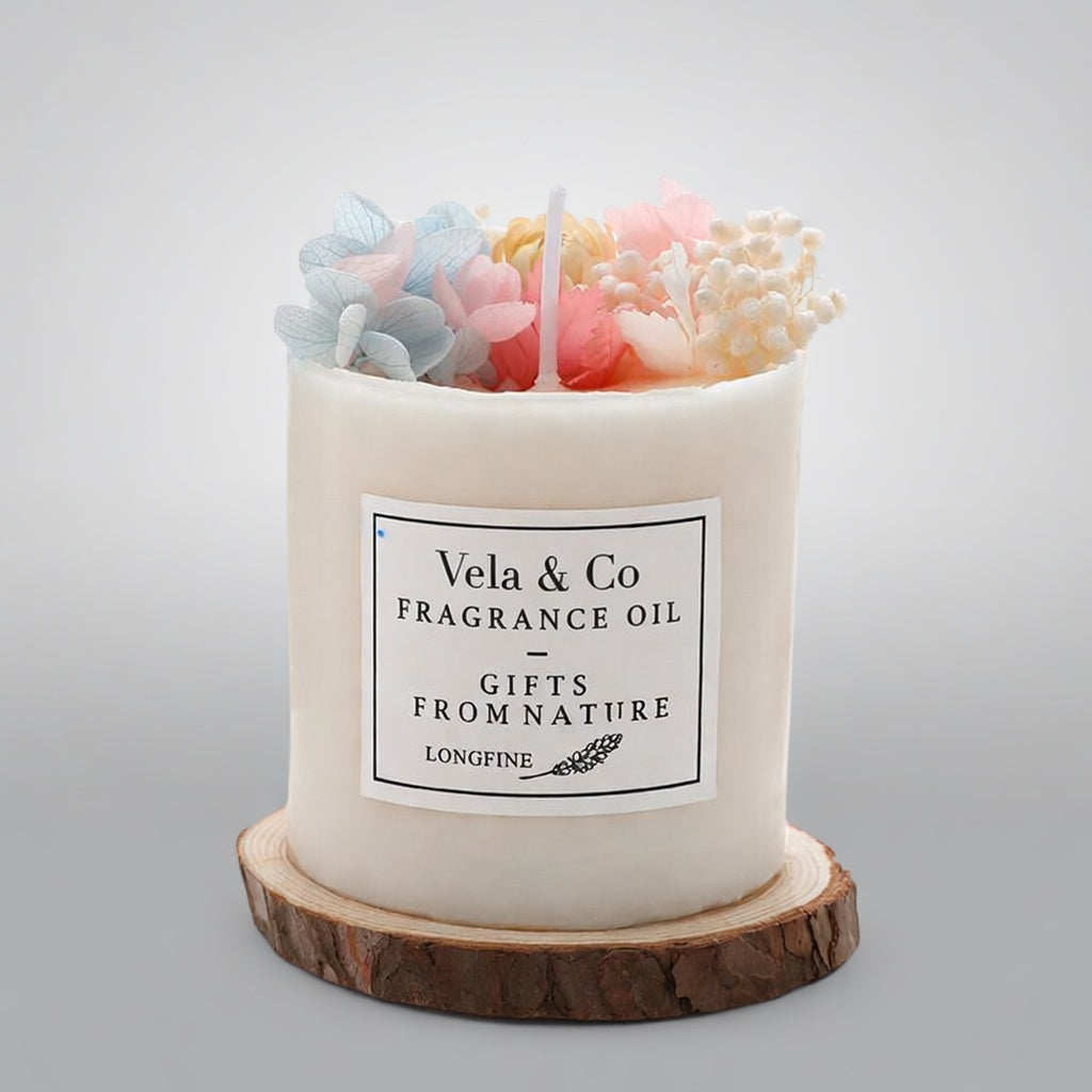 Vela Sanctuary scented candle topped with pastel blue and pink dried flowers on a wood slice